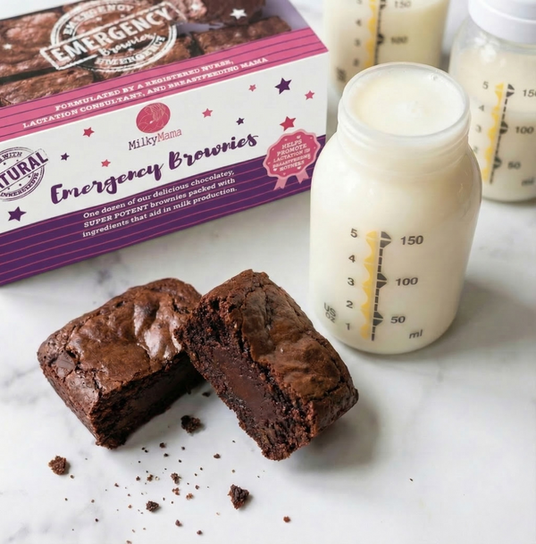 Chocolate brownie, Milky Mama Emergency Brownies packaging, and bottles of milk on a marble surface.